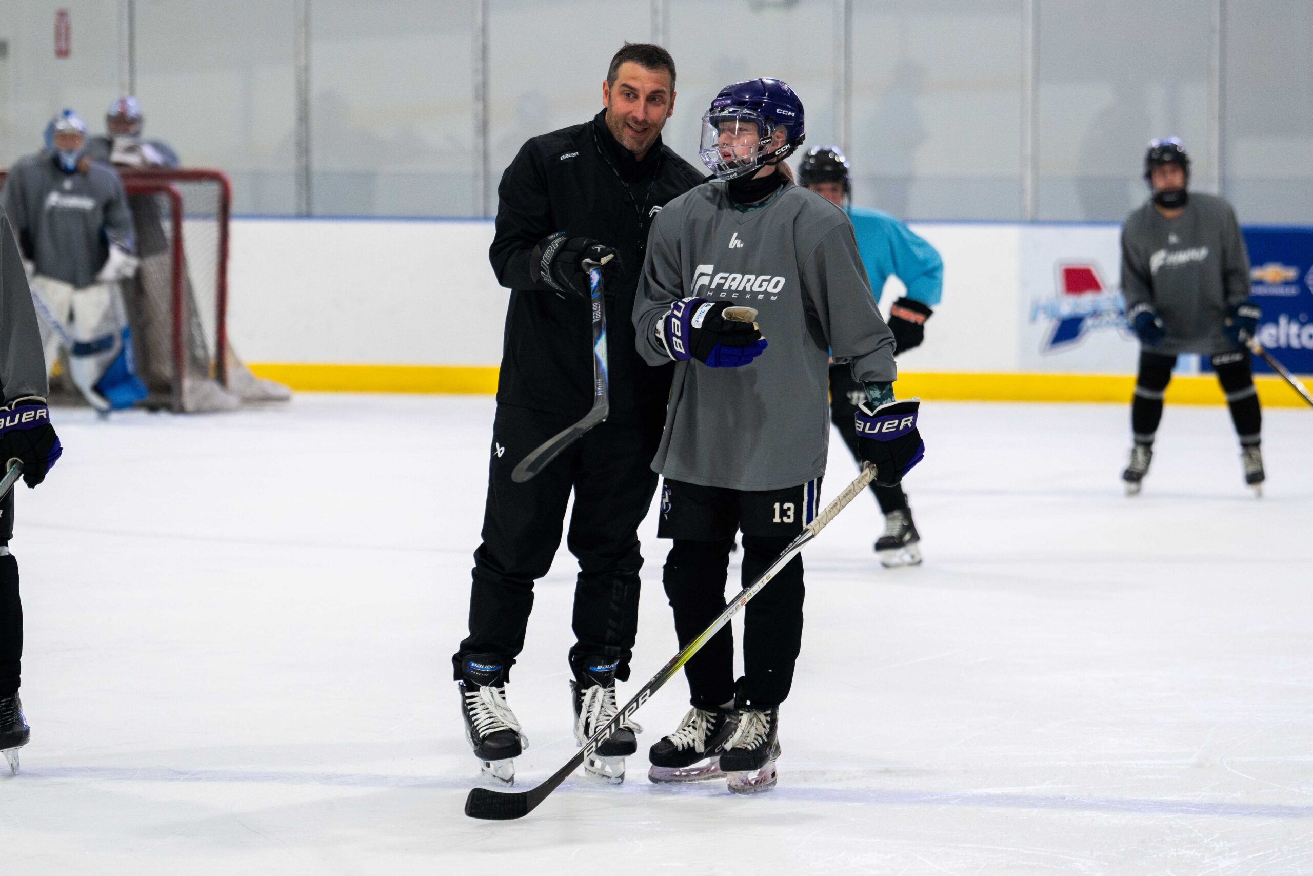 Coach giving one-on-one instruction to a camper on the ice