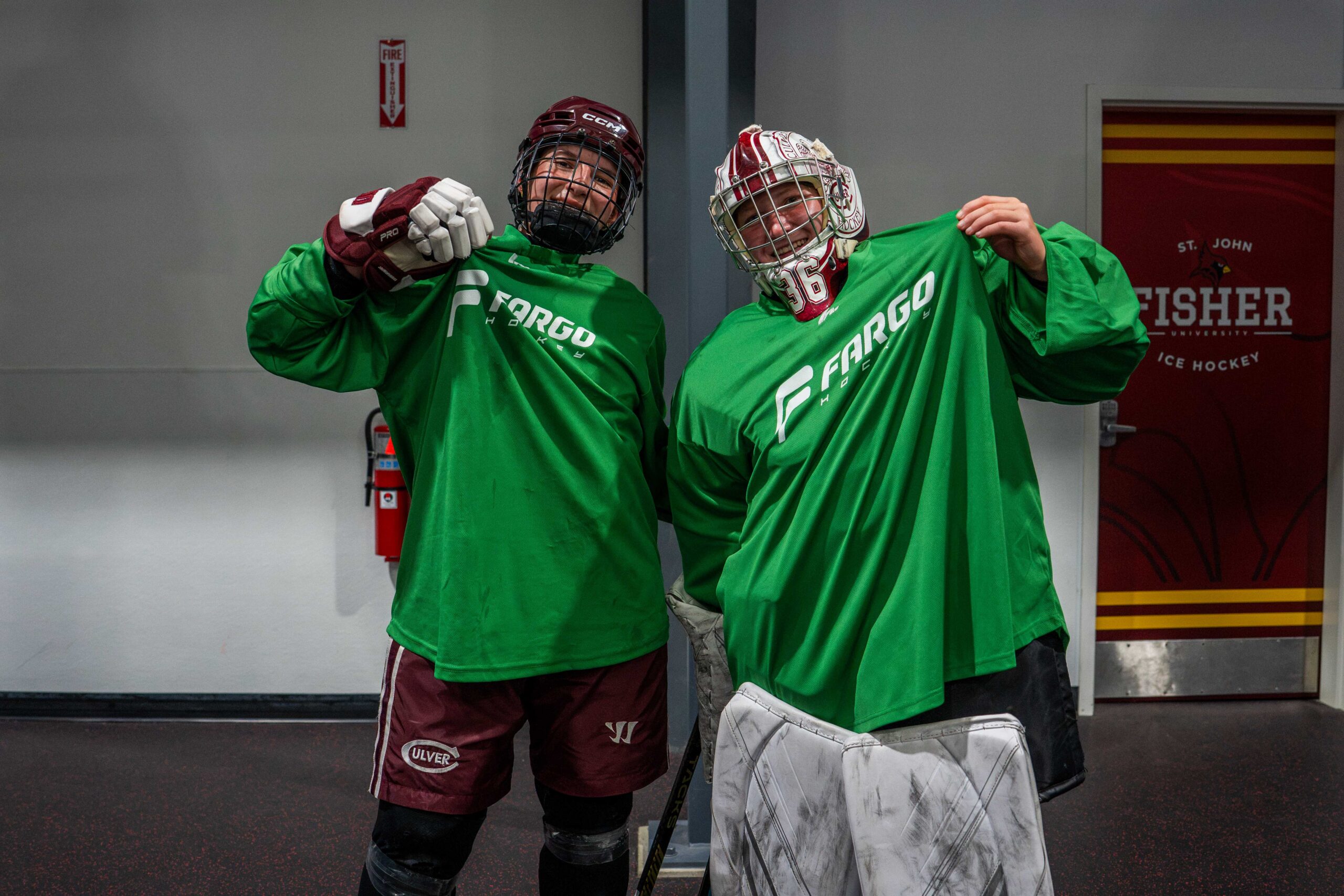 Two campers in green Fargo Hockey jerseys smiling