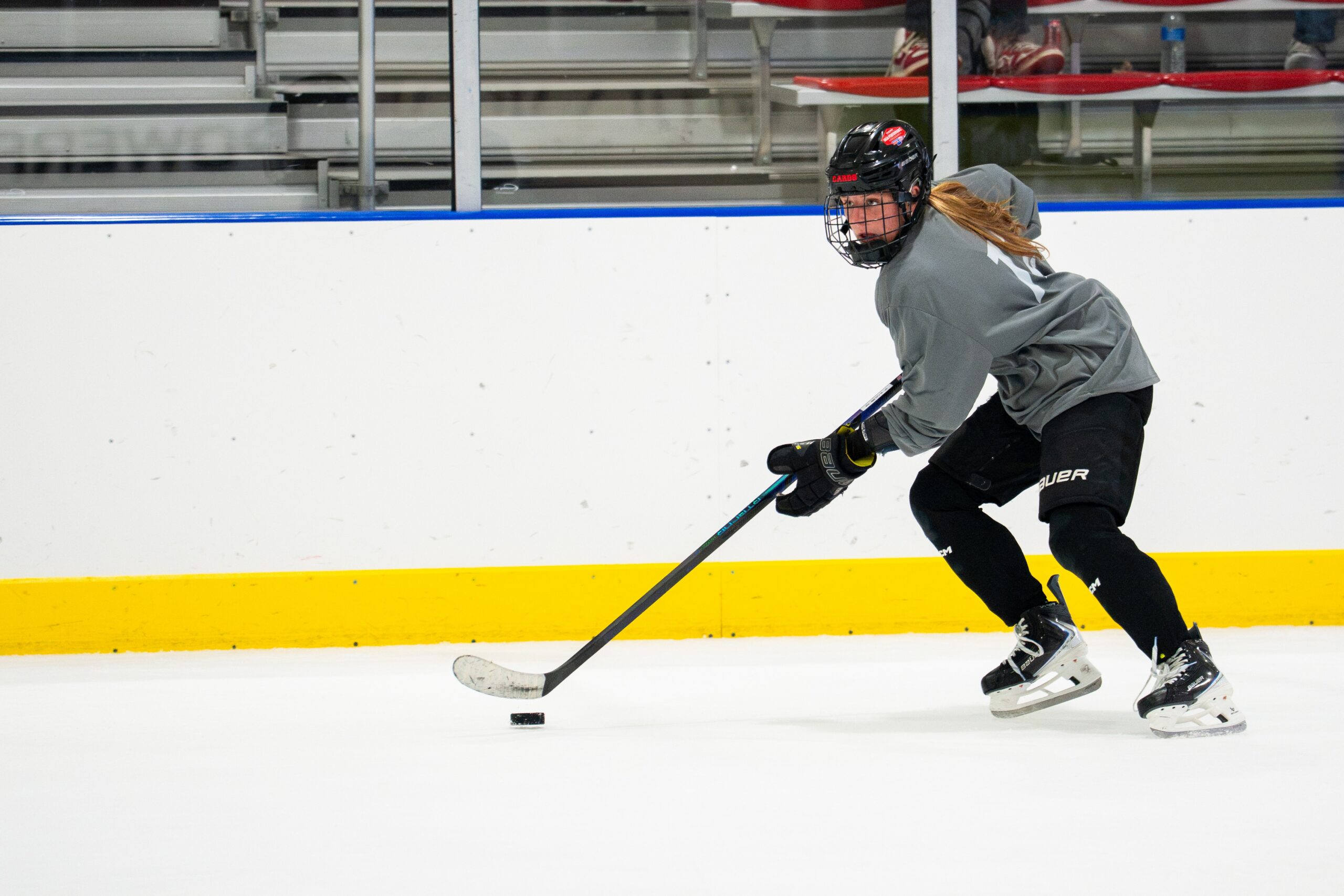 Camp player carrying the puck up ice during a drill